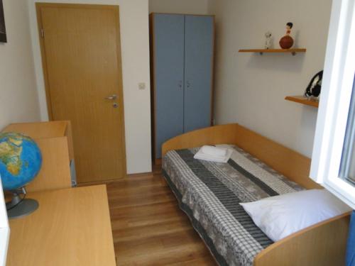 a small room with a bed and a desk and a room with a globe at Apartman Hana in Šibenik