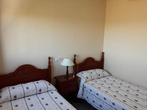 a bedroom with two beds and a lamp on a nightstand at Vivienda Rural Alcazaba in Chipiona