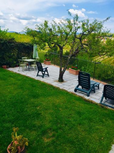 a patio with benches and a table and a tree at Casa vacanza vicolo degli orti in Monticiano
