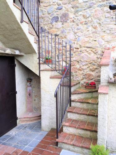 a stone building with stairs and a black door at Casa vacanza vicolo degli orti in Monticiano