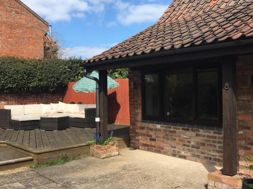a pavilion with a couch and umbrella on a deck at The Stables At Harby in Melton Mowbray