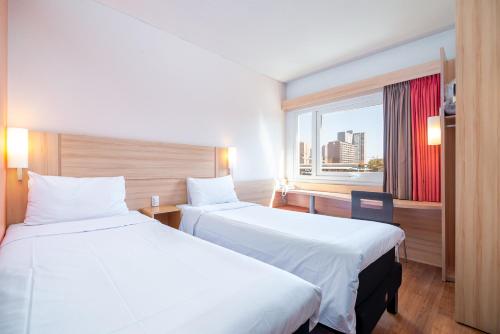 
a hotel room with two beds and two lamps at ibis Santiago Estacion Central in Santiago
