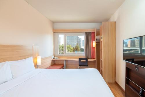 um quarto de hotel com uma cama, uma secretária e uma janela em ibis Santiago Estacion Central em Santiago