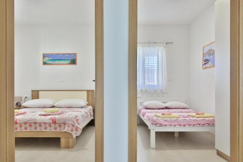 2 Betten in einem Zimmer mit Spiegel in der Unterkunft Apartments Mica in Vrsi