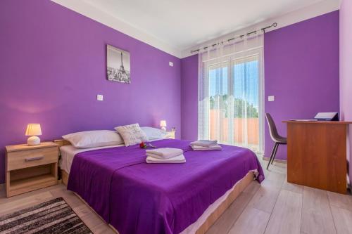 purpurowa sypialnia z łóżkiem i fioletowym kocem w obiekcie Apartmani Vesna w mieście Opric