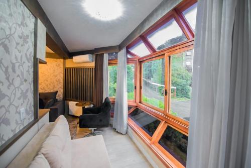 a living room with a couch and a large window at Flat no Hotel Wish Serrano Resort in Gramado