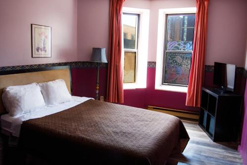 a bedroom with a bed and a television and windows at Hotel Casa Bella in Montréal