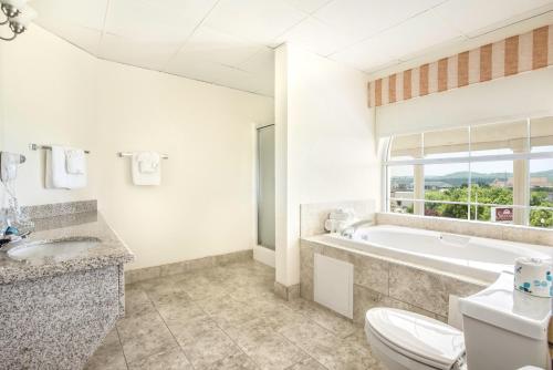 a bathroom with a tub and a toilet and a sink at Savannah House Hotel in Branson