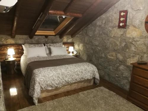 a bedroom with a bed and a stone wall at Casa rural La Borriquita in Gavilanes