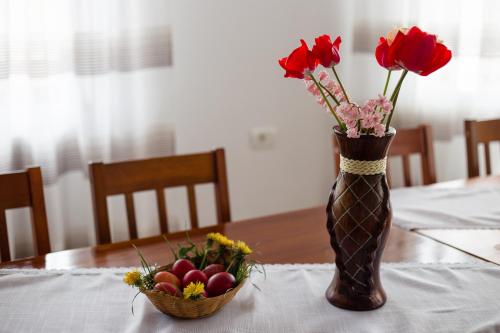 a vase with roses and a basket of fruit on a table at Angela in Polovragi