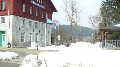 a large red building with snow in front of it at Pension na hranici in Železná Ruda