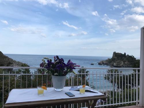 a table with a vase of flowers on a balcony at Paradisea Taormina in Taormina