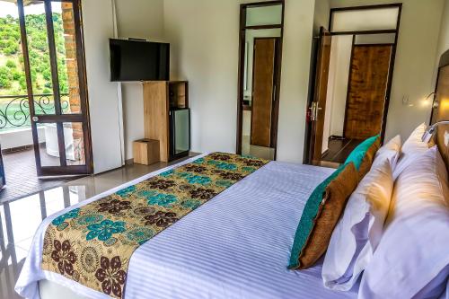 a bedroom with a bed with a television and a balcony at Hotel La Magdalena Adult Only in Guatapé