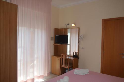 a bedroom with a bed and a television and a window at Hotel Karin in Rimini