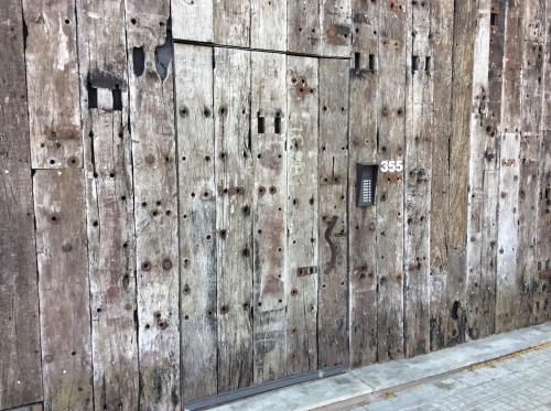 a wooden wall with a door on the side of a street at Las Glicinas Boutique Apartments in Colonia del Sacramento