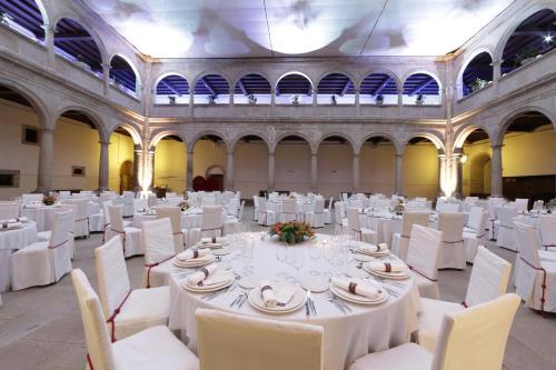 a large room with white tables and white chairs at San Francisco Hotel Monumento in Santiago de Compostela