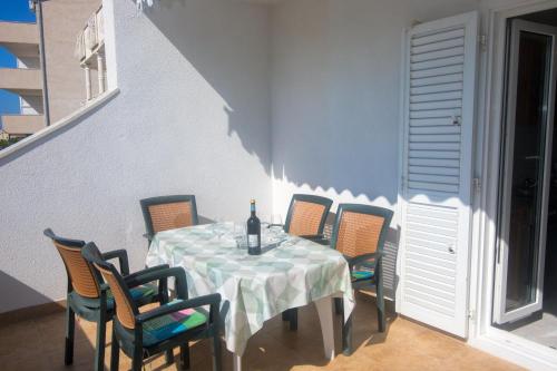 una mesa con sillas y una botella de vino. en Apartments Vinka en Trogir