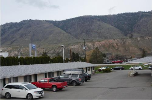 a parking lot with cars parked in front of a mountain at Trans Canada Motel in Kamloops