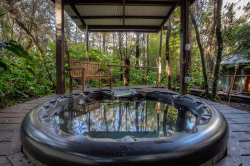 a hot tub on a patio with a bench at Volcano Mist Cottage in Volcano