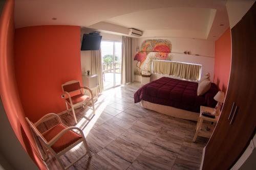 a bedroom with orange walls and a bed and a window at Punta Encanto Posada Boutique in Miramar