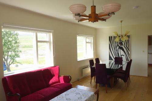 ein Wohnzimmer mit einem roten Sofa und einem Tisch in der Unterkunft Thorbrandsstadir Farm Holidays in Þorbrandsstaðir