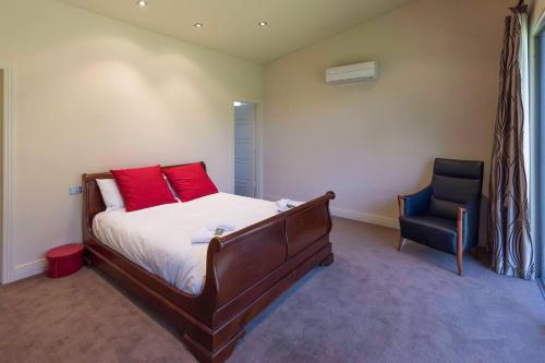 a bedroom with a bed with red pillows and a chair at 141 Providence Drive, Bowhill in Bow Hill