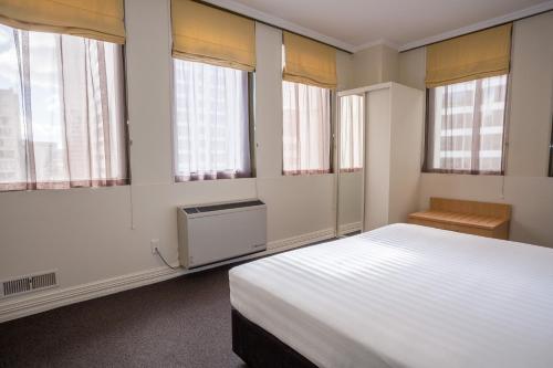 a bedroom with a large white bed and windows at Edit Auckland Central in Auckland