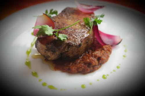 a white plate with a piece of meat and vegetables at Merida Santiago Hotel Boutique in Mérida