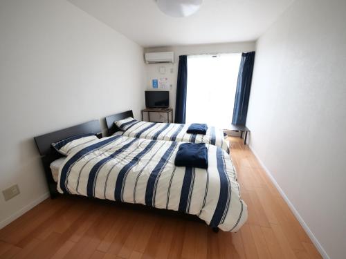 een slaapkamer met een bed met een gestreept dekbed en een raam bij VistaMare in Kanoya
