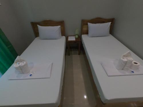 two beds in a room with white sheets at Morning Star Hotel in San Vicente