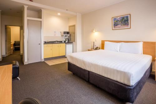 a hotel room with a large bed and a kitchen at President Hotel Auckland in Auckland
