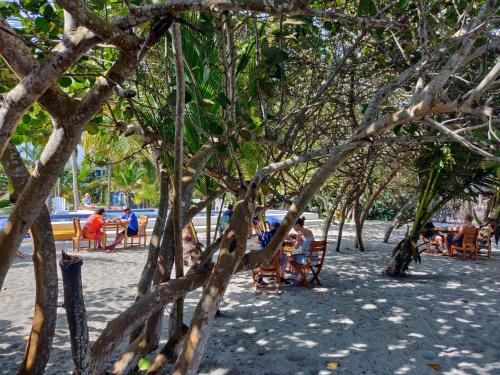 people sitting on a bench under umbrellas at Blue Mango Beach Hotel in Guachaca