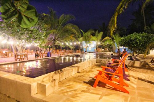 a swimming pool with chairs and tables at night at Blue Mango Beach Hotel in Guachaca
