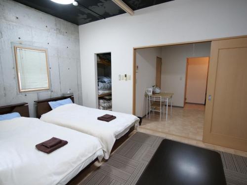 鹿屋市にあるSRマンションのベッド2台とテーブルが備わる客室です。