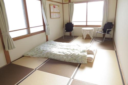 a bedroom with a bed and two chairs and windows at Traveler's Inn Asanebo in Teshikaga