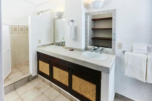 a white bathroom with two sinks and a mirror at Hotel Suites Ixtapa Plaza in Ixtapa