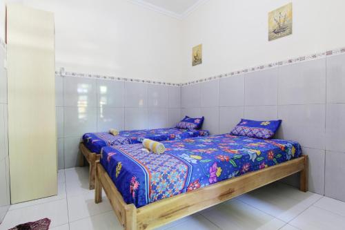 a bedroom with a wooden bed with purple sheets at Losmen Alden in Yogyakarta