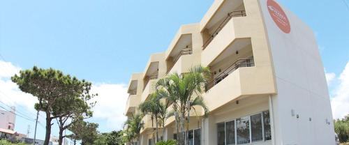 a building with palm trees in front of it at Marine Lodge Marea Ishigaki in Ishigaki Island