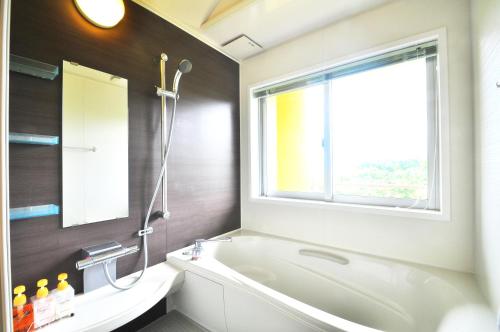 a bathroom with a bath tub and a window at Marine Lodge Marea Ishigaki in Ishigaki Island