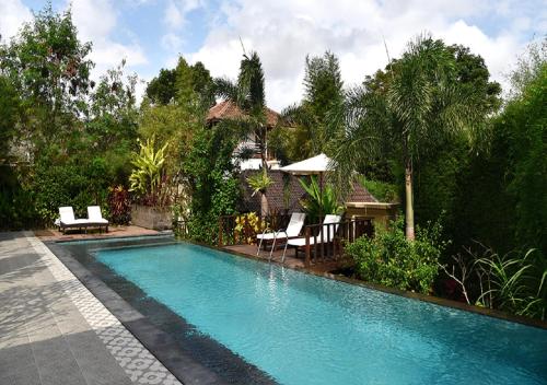 a swimming pool in a yard with chairs and trees at Villa with private pool at Villa Nirvana Ubud in Ubud