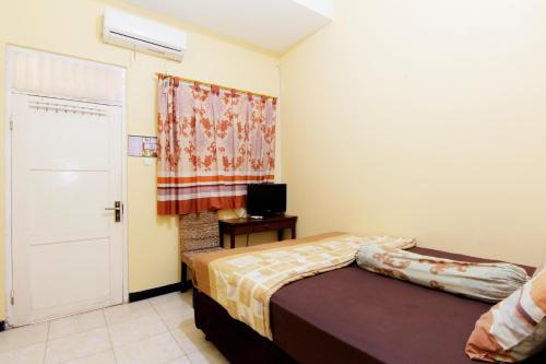 Dormitorio pequeño con cama y TV en JJ House Gejayan, en Yogyakarta