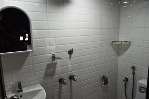 a white tiled bathroom with a sink and a mirror at Sea Hut Homestay in Cochin