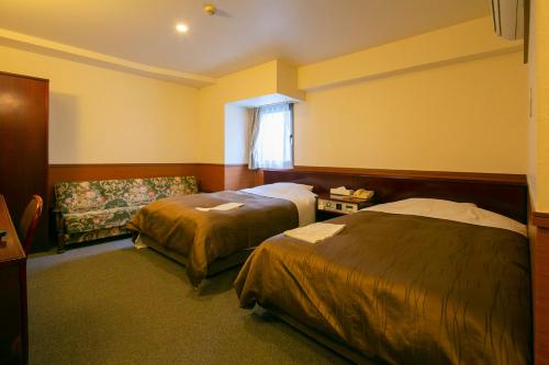 a hotel room with two beds and a couch at Nanshukan in Kagoshima