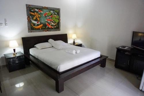 a bed in a room with two tables and a tv at Ary Guest House in Canggu