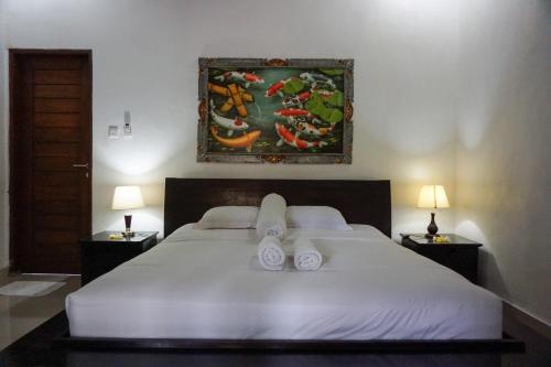 a bedroom with a large white bed with two lamps at Ary Guest House in Canggu