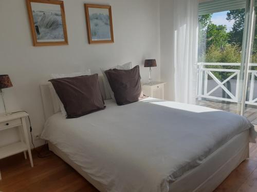 - un lit blanc dans une chambre avec fenêtre dans l'établissement La Maison Blanche, à Andernos-les-Bains