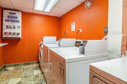 pralnia z pomarańczowymi ścianami oraz pralką i suszarką w obiekcie Motel 6-Joliet, IL - I-80 w mieście Joliet