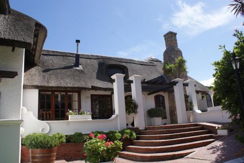 a house with a thatched roof and stairs at Whale Rock Luxury Lodge in Hermanus