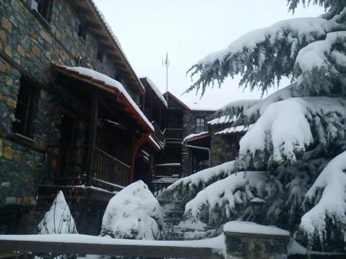 a house with snow on the side of it at Chalet Asteras tou Vorra in Palaios Agios Athanasios