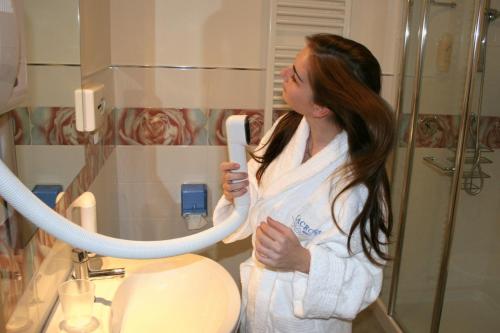 a woman standing in a bathroom holding a toothbrush at Lacroma Aparthotel in Grado